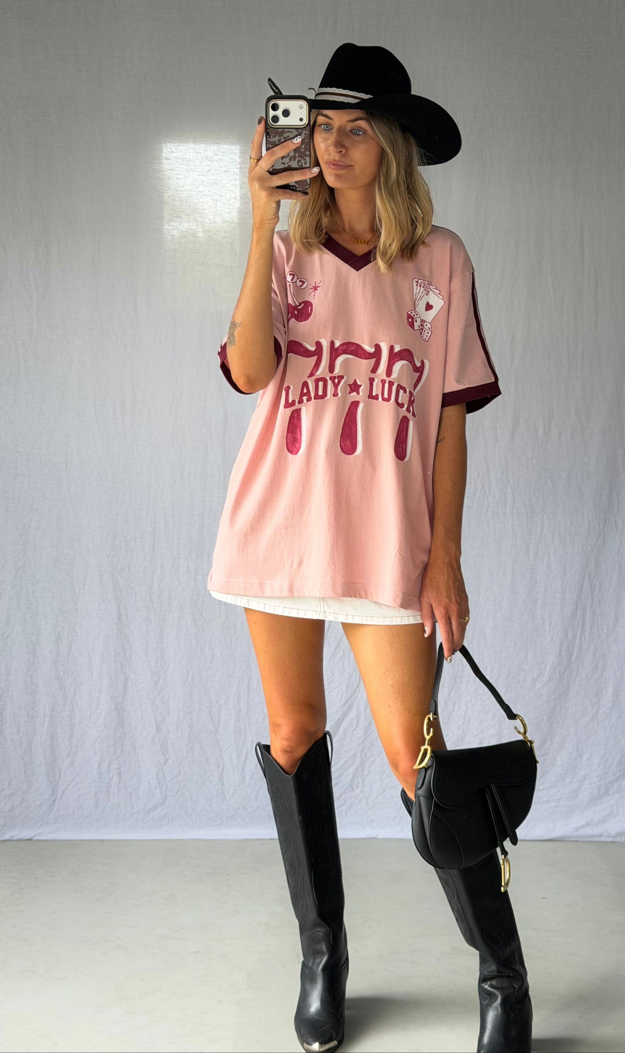 the Lucky Girl Tee is all about confidence, intuition, and calling in good things. Inspired by lucky motifs and the angel number 777, this women’s graphic tee blends playful symbolism with a bold, feminine edge. Pink base with burgundy trim for a flattering contrast. Jersey style vintage cotton.
The artist hand drawn art  western-style numbers and star detailing, finished with cherries, playing cards and dice graphics for a nostalgic, Americana-inspired feel.