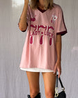 the Lucky Girl Tee is all about confidence, intuition, and calling in good things. Inspired by lucky motifs and the angel number 777, this women’s graphic tee blends playful symbolism with a bold, feminine edge. Pink base with burgundy trim for a flattering contrast. Jersey style vintage cotton.
The artist hand drawn art  western-style numbers and star detailing, finished with cherries, playing cards and dice graphics for a nostalgic, Americana-inspired feel.